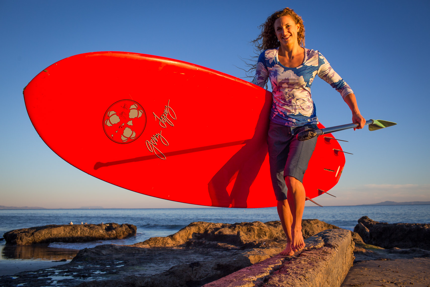 Woman Carrying a Gerry Lopez SUP Surf Board