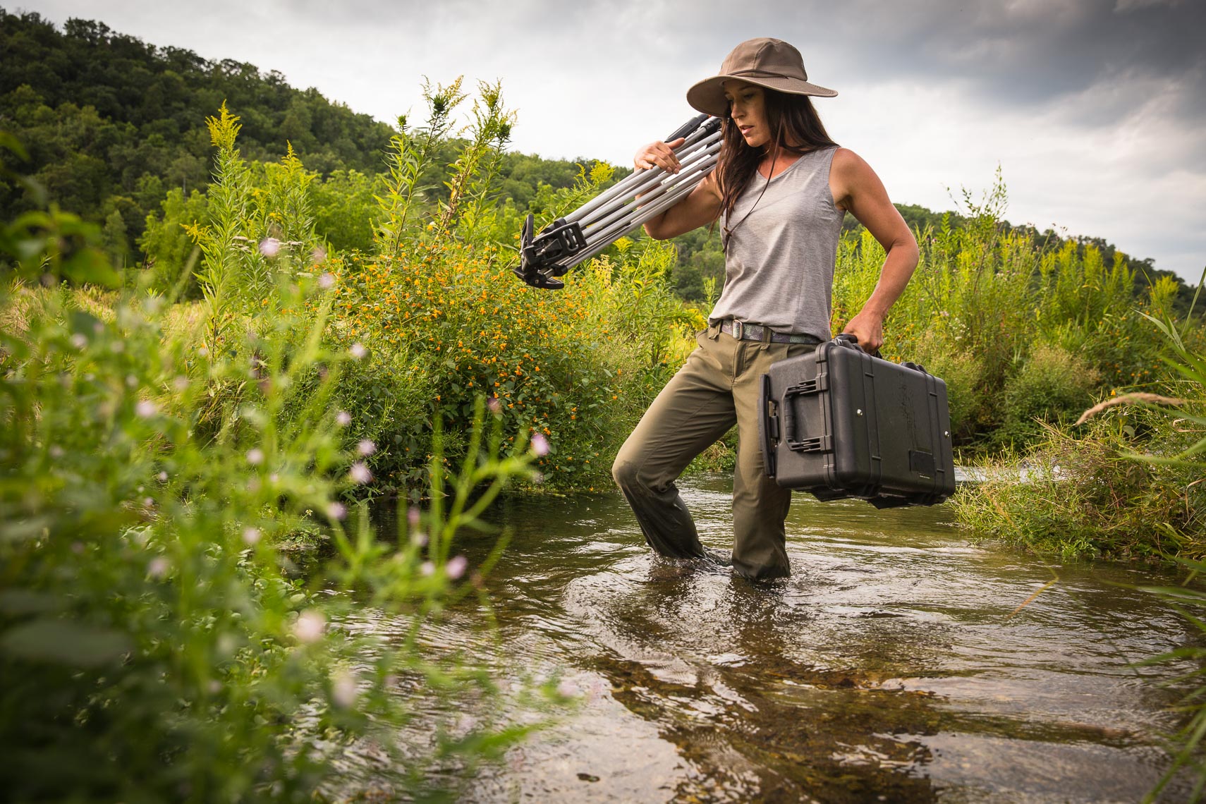 Director of Photography Carrying Tripod and Camera Across River